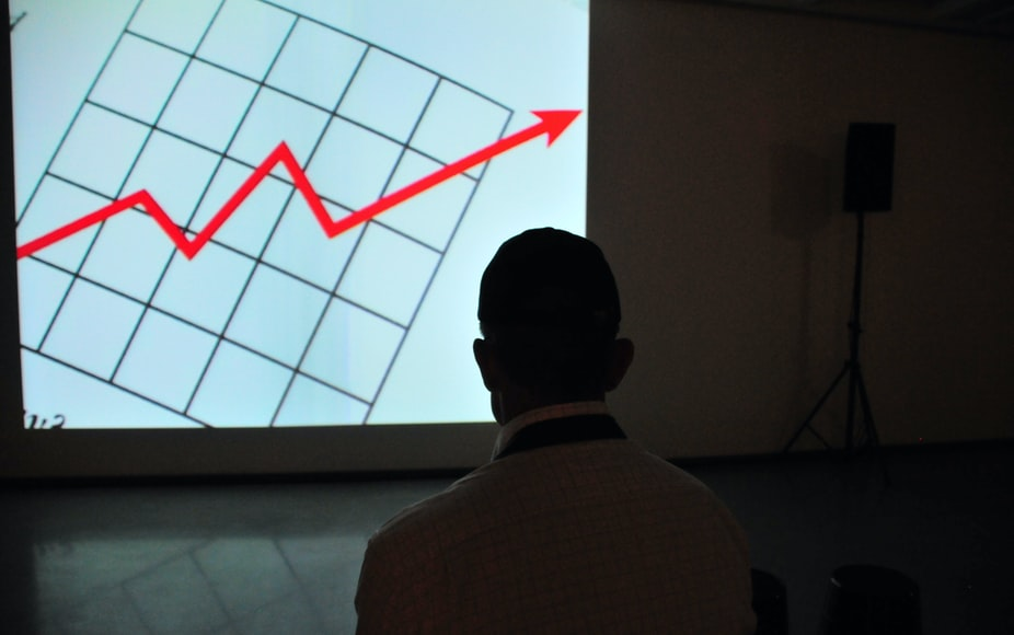 A man in front of a screen with a red arrow